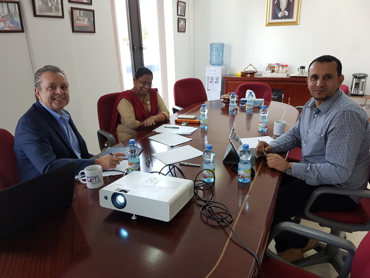 Three people sit around a conference table.