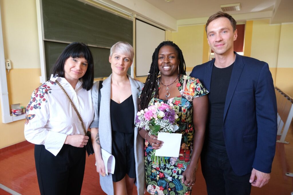 A group of four adults standing together side by side and smiling.