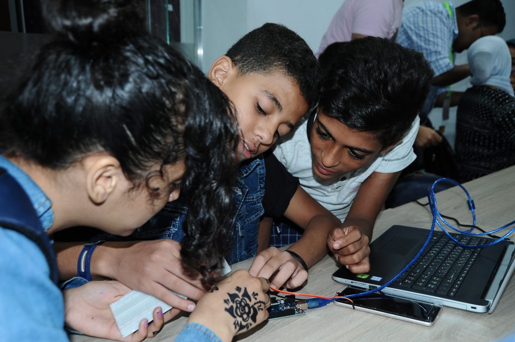 Four students work on a circuit board.
