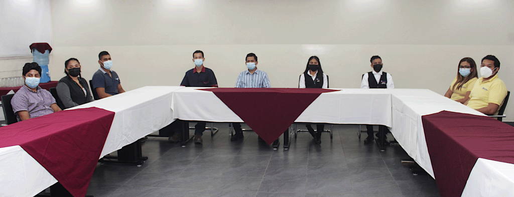 A group of young people sit around a U-shaped table in a conference room.