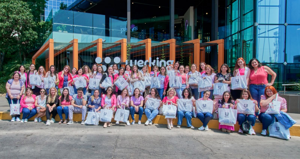 A large group of adult women pose together holding tote bags.