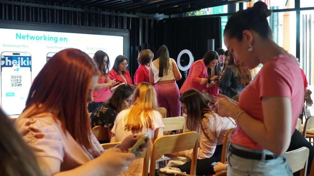 A group of adults sharing contact information over their phones during a networking session.